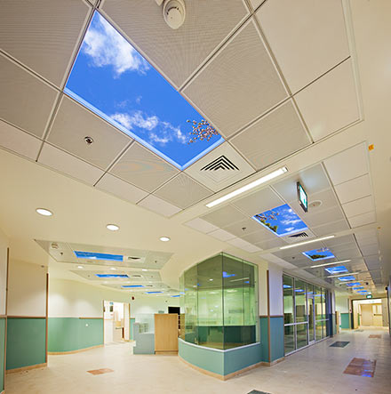 Corridors around the centrally located nursing stations feature dozens of virtual skylights providing valuable biophilic stimulation in the windowless interior.